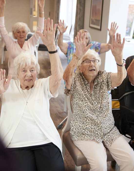 carer-leading-group-of-seniors-in-fitness-class-in-retirement-home.jpg